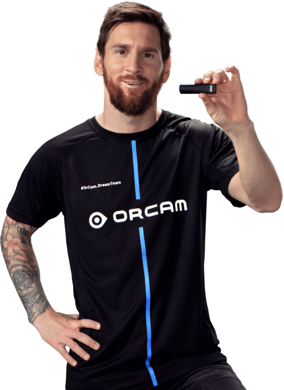 Leo Messi, holding an OrCam MyEye device while wearing an OrCam jersey.